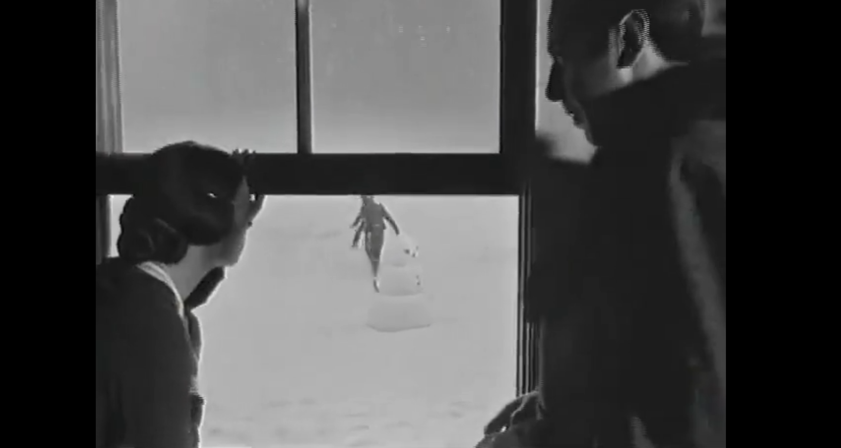 still from opening of Citizen Kane where CFK is playing in the snow and his mother is talking to Mr. Thatcher
