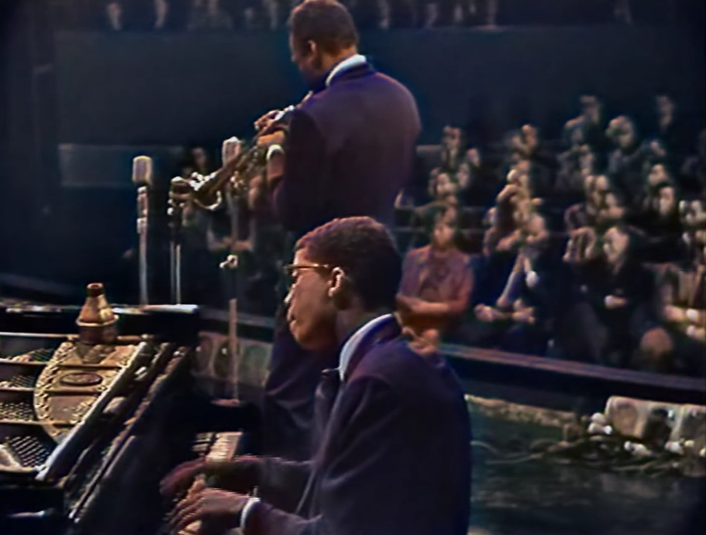Miles Davis and Herbie Hancock in suits playing on stage in 1965